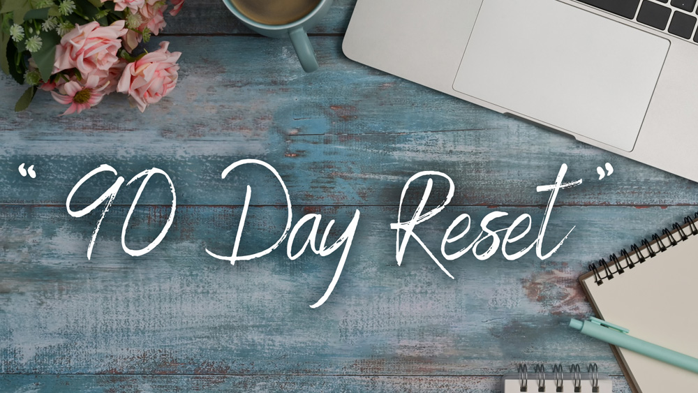 Overhead view of a journal titled '90 Day Reset' with a cup of coffee