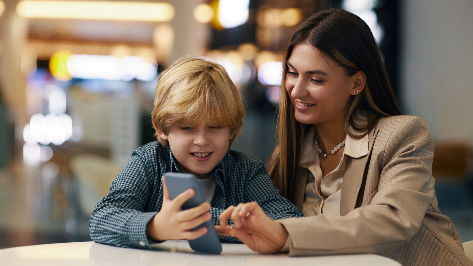 Child sharing travel photos with fellow airport traveler