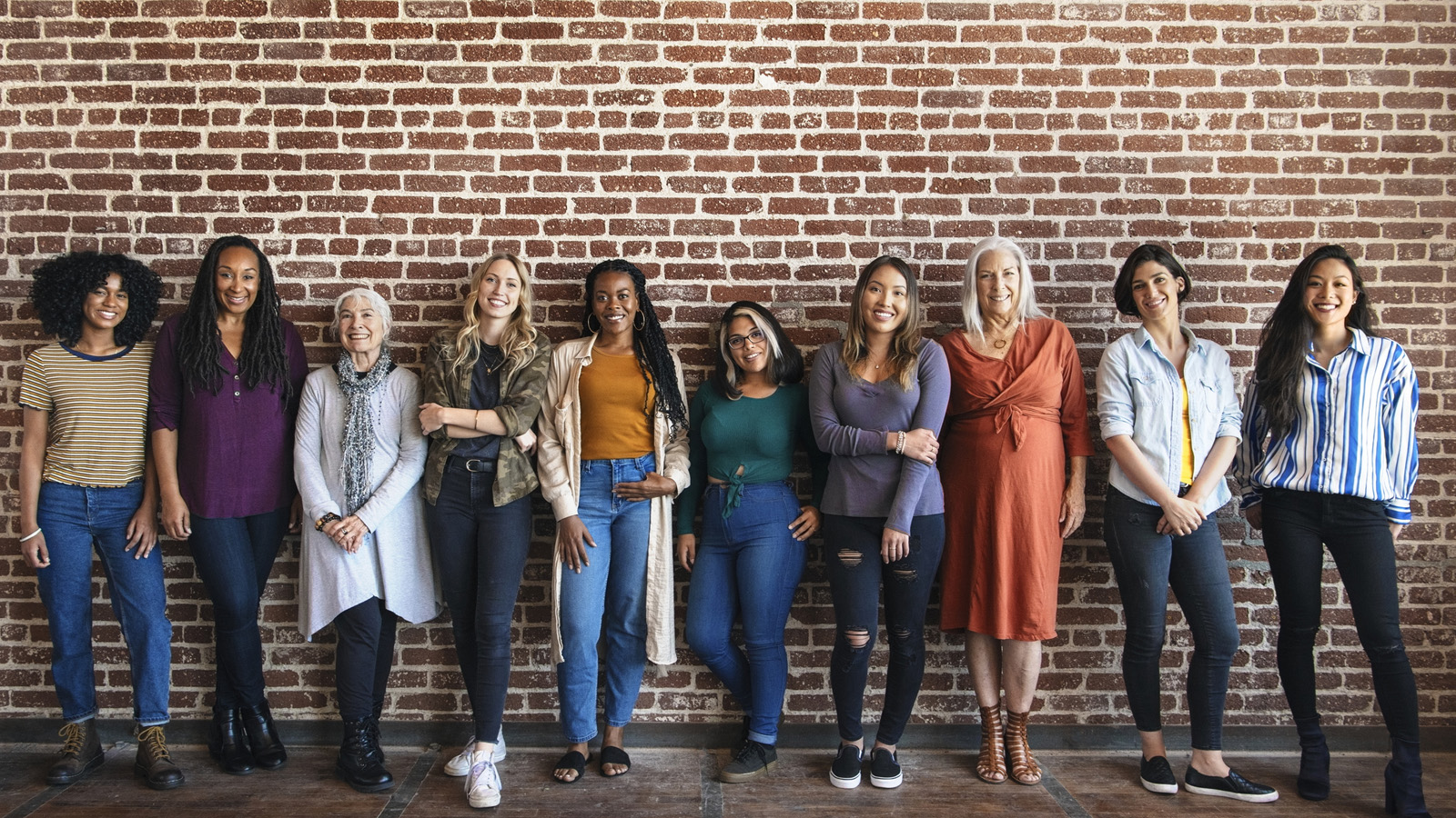 Happy woman standing by a brick wall.